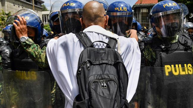 A Catholic priest tries to speak to police at a rally in front of the electoral commission in Manila. Picture: AFP