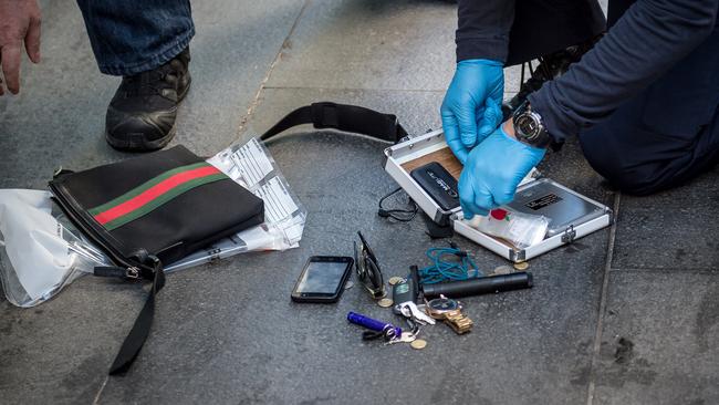 Police search through the man’s possessions. Picture: Jake Nowakowski