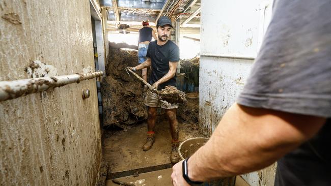 Lucas Chabreyroux shovels mud out of the Ellis Beach Bar and Grill. Picture: Brendan Radke