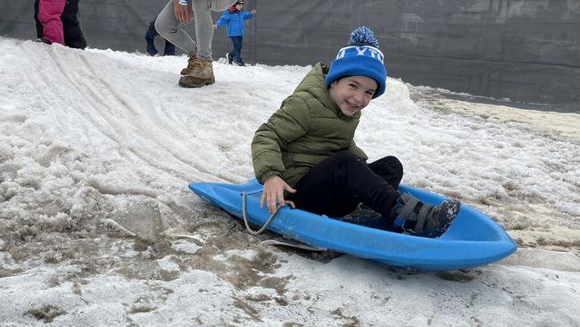 Six-year-old Phoenix Morrissey slides down the snow hill on the toboggan at the Snowflakes in Stanthorpe snowfields on day 2 of the 2021 festival. Photo: Madison Mifsud-Ure / Stanthorpe Border Post