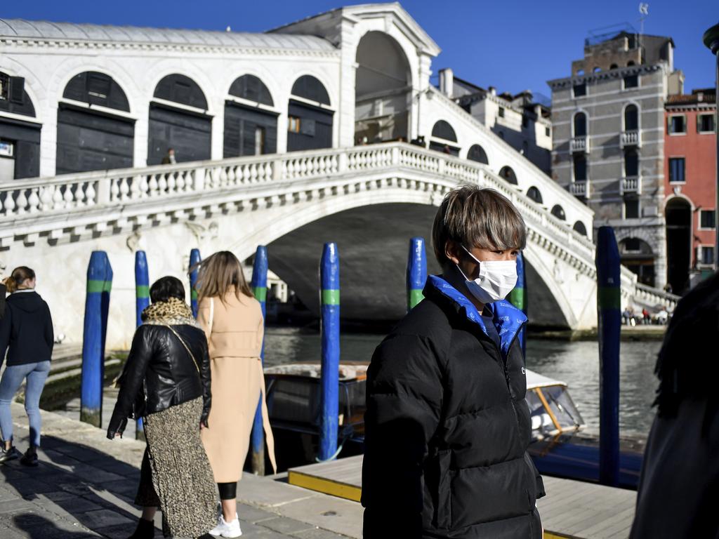 A man wearing a protective mask walks past the Ponte di Rialto (Rialto Bridge) in Venice, Italy. Picture: Claudio Furlan/Lapresse/AP.