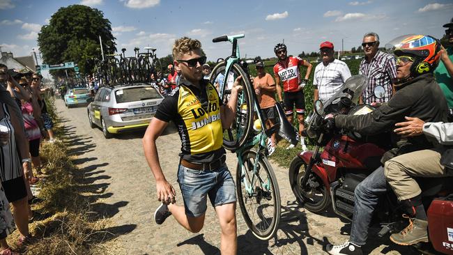 A Netherlands' Team Lotto/NL Jumbo cycling team staffer rushes to being a new bicycle to Netherlands' Dylan Groenewegen, winner of the previous stage, after he crashed on the cobblestones.