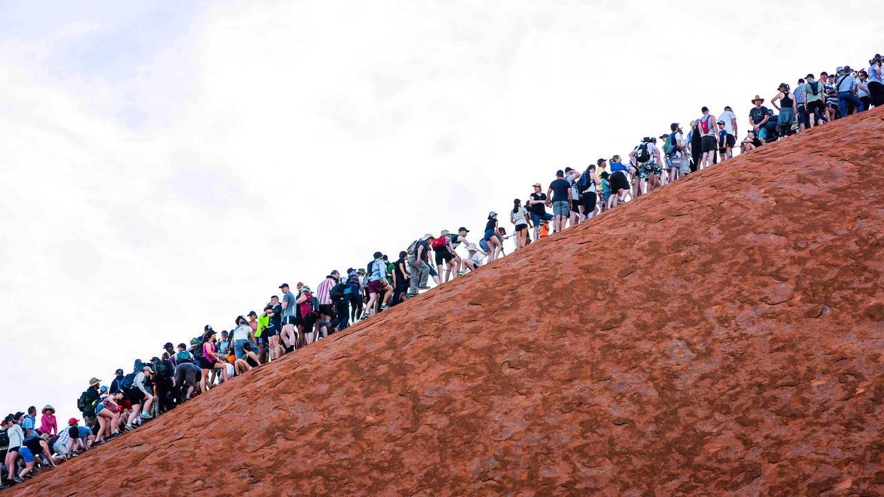 Hordes of climbers pictured heading up Uluru in Uluru-Kata Tjuta National Park on one of the last days before the climb closes.