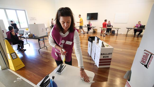 An election official sanitizes a table at a polling booth in Brisbane. Picture: Getty