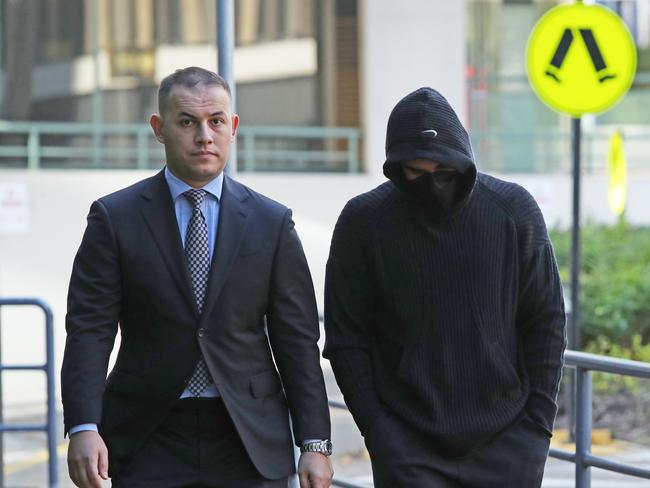 Adam Abdallah (right, wearing black) arrives at Bankstown Police Station with his lawyer Talal Krayem on Sunday afternoon. Picture: Richard Dobson