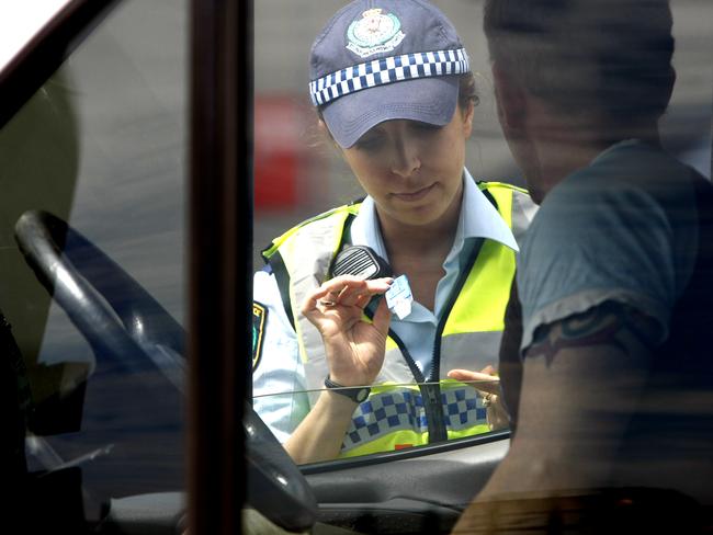 A police officer performs a random drug test. Police from the Kings Cross Local Area Command perform random breath tests and drug tests along Cowper Wharf Road, Woolloomooloo. GEneric, police, RBT, random breath test, alcohol, drink driving