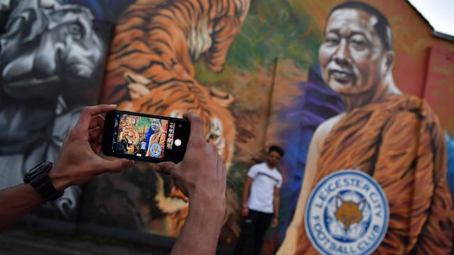 A man poses for a photograph against a mural showing Leicester’s owner.