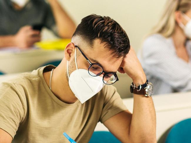 College students wearing protection N95 mask due to covid19 pandemic and sitting in the classroom