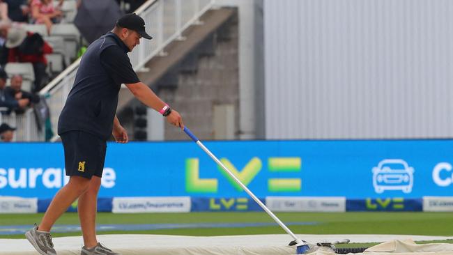 A member of the groundstaff works to clear the water. Picture: AFP