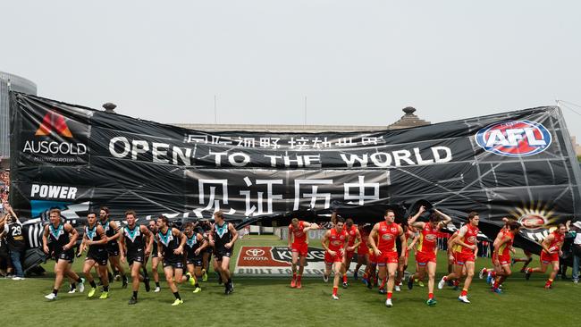 Players run through a joint banner for the start of the Port-Gold Coast match in Shanghai. Picture: Michael Willson/AFL Media