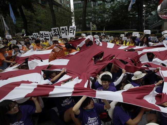 Angry ... South Korean students tear a huge Japanese rising sun flag during a rally denouncing Japanese Prime Minister Shinzo Abe's statement. Picture: AP