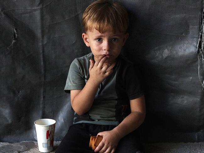 A child sits holding his biscuits at the Jabalia camp for displaced Palestinians in northern Gaza on August 29, 2024, amid the ongoing conflict between Israel and the militant Hamas group. (Photo by Omar AL-QATTAA / AFP)