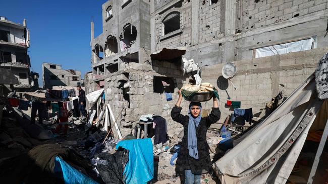 A woman carries bread next to destroyed houses in Rafah on the southern Gaza Strip. Picture: Mohammed Abed / AFP