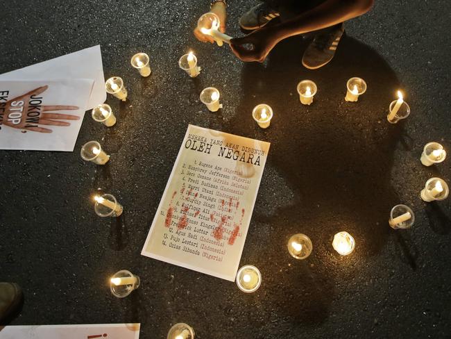 An activist lights candles arranged around a poster containing the names of death row inmates who are facing imminent executions. Picture: Dita Alangkara