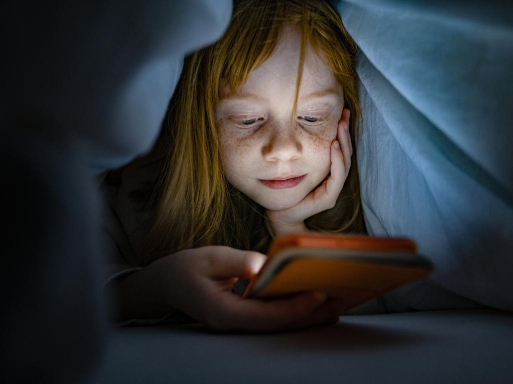 Girl using a mobile phone in the night. Kid skipping sleep hooked on the phone