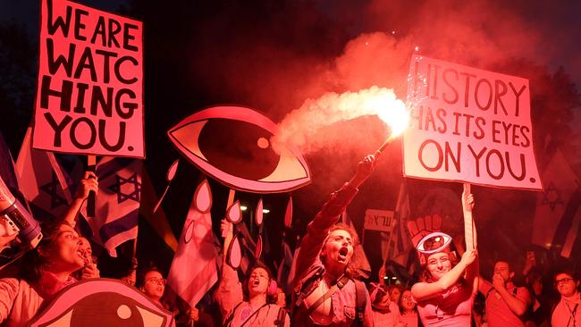 Demonstrators lift placards and use flares during a rally to protest the Israeli government's judicial overhaul bill in Tel Aviv on April 29. Picture: AFP