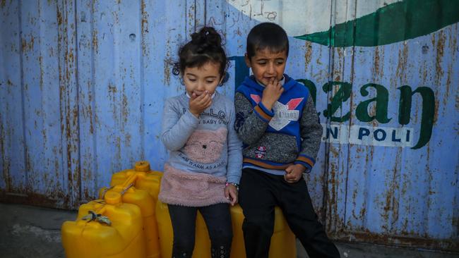 Palestinian children sit on containers at a water filling station in Rafah, Gaza. Picture: Ahmad Hasaballah/Getty Images