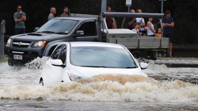 A car attempts to make its way through flood water after the Tallebudgera Creek burst its banks at the western end of 19th Avenue, Elanora. Photo: Scott Powick