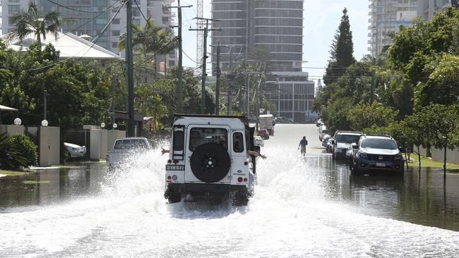 A four-wheel drive charges into floodwater on Palm Ave at Budds Beach at high tide this morning. Picture Glenn Hampson