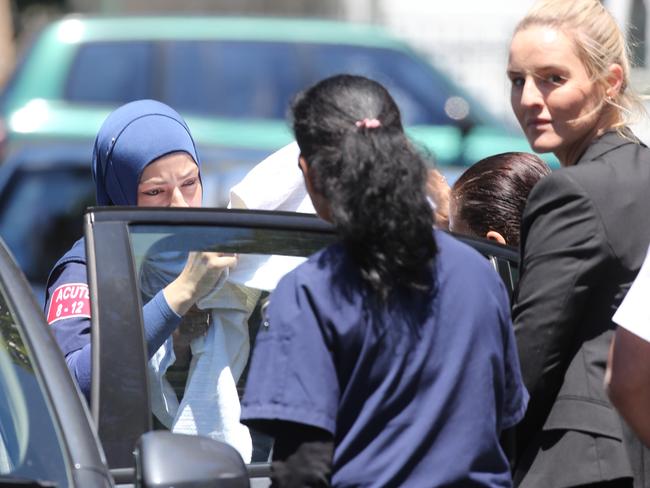 A woman believed to be Maha Al-Shennag is taken out of Bankstown hospital via a side exit hidden under a blanket and bundled into an unmarked police car. Picture: John Grainger