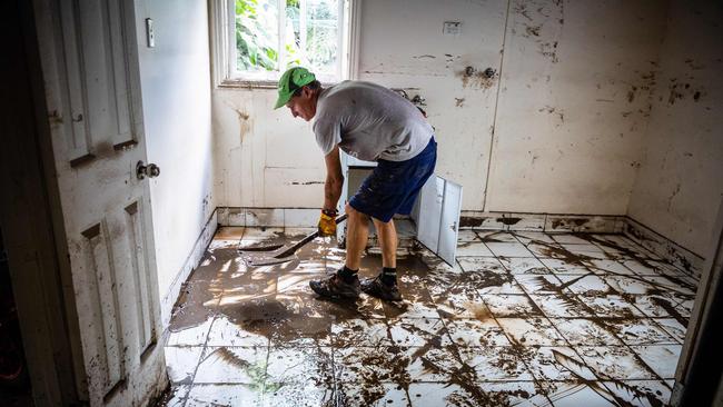 A man shovels mud from the lower level of a home in Newmarket, Brisbane. Picture: Patrick Hamilton/AFP