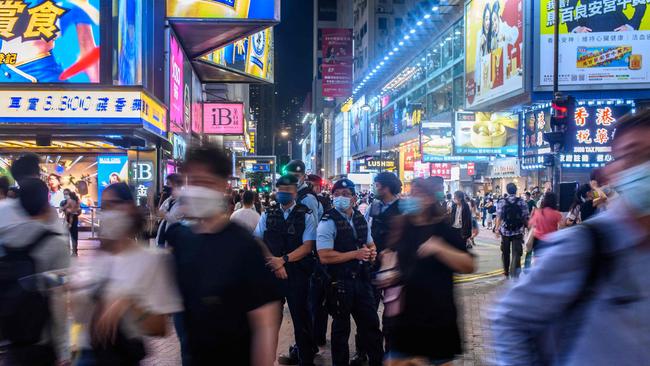 Police standing guard as pedestrian walk past in the shopping district of Causeway Bay. Picture: Anthony Wallace, AFP.