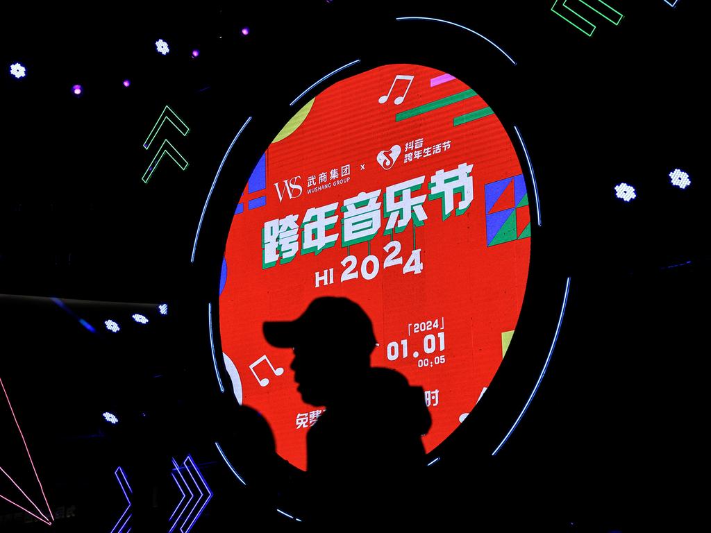 A man passes a screen during the New Year music festival at WS mall in Wuhan on December 31, 2023. Picture: Getty Images