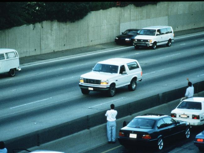 Motorists wave as police cars pursue the Ford Bronco (white, R) driven by Al Cowlings, carrying fugitive murder suspect O.J. Simpson, on a 90-minute slow-speed car chase June 17, 1994 on the 405 freeway in Los Angeles, California. Picture: Jean-Marc Giboux/Liaison