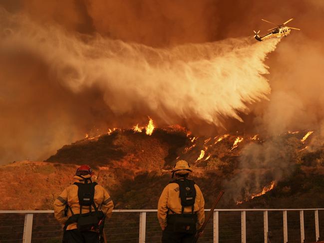 Firefighters watch as water is dropped on the Palisades Fire in Mandeville Canyon on Saturday, Jan. 11, 2025, in Los Angeles. (AP Photo/Jae C. Hong)