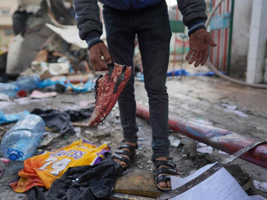 A Palestinian lifts a blood-soaked shoe from the debris of a container at an UNRWA school used to shelter displaced people, after it was hit in Israeli bombardment on Nusseirat in the central Gaza Strip. Picture: AFP