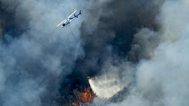 A helicopter drops water on a bushfire, working from Peregian Beach towards Weyba Downs on the Sunshine Coast, Queensland. Picture: Lachie Millard