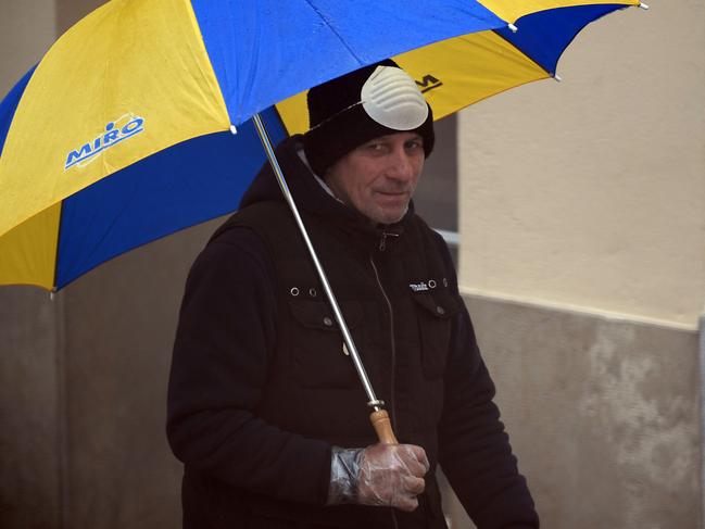 A man gives himself a brief respite from wearing a face mask as he walks in Vilanova I la Geltru in Italy. Picture: AFP