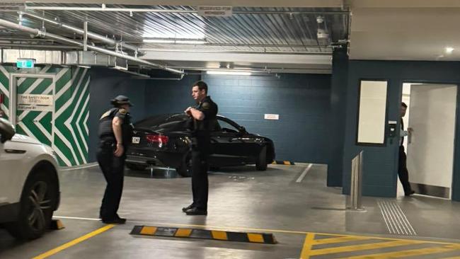 Police with the black Audi after it rammed into a roller door leading to a secure carpark at Parliament House. Picture: Supplied