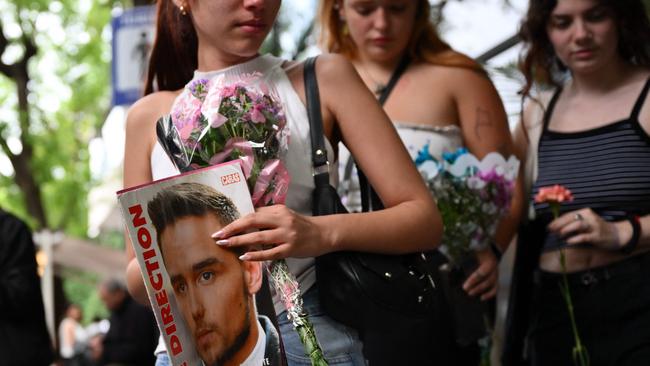 A fan holds a magazine with a photo of British singer One Direction fans worldwide mourn the loss of Payne, 31. Picture: Luis Robayo/AFP