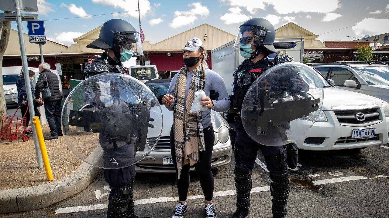 A woman is detained by Victoria Police at the market. Picture: Darrian Traynor/Getty Images