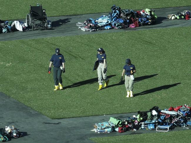 Members of the FBI walk among piles of personal items at the scene. Picture: AP