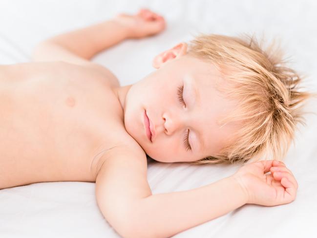 Close-up portrait of little boy with blond hair sleeping on white bad. Carefree childhood concept. istock image