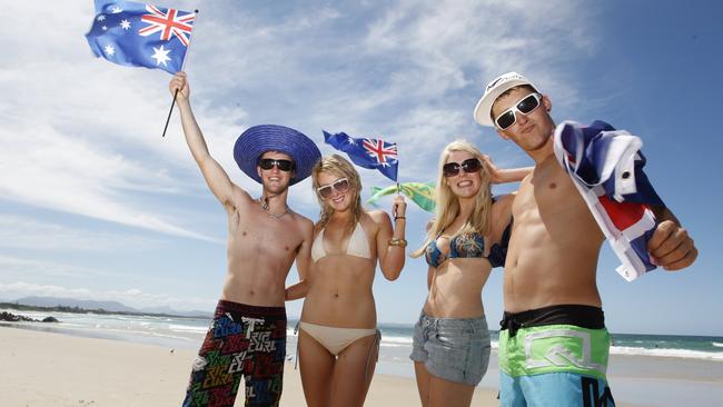 (L-R) Luke Streets, Honnie Harris, Sophie Eade and Tyson Skipper, from Launceston in Tasmania, pose for portrait holding Australia day flags at Main Beach, Byron Bay. Photo Jerad Williams / The Northern Star