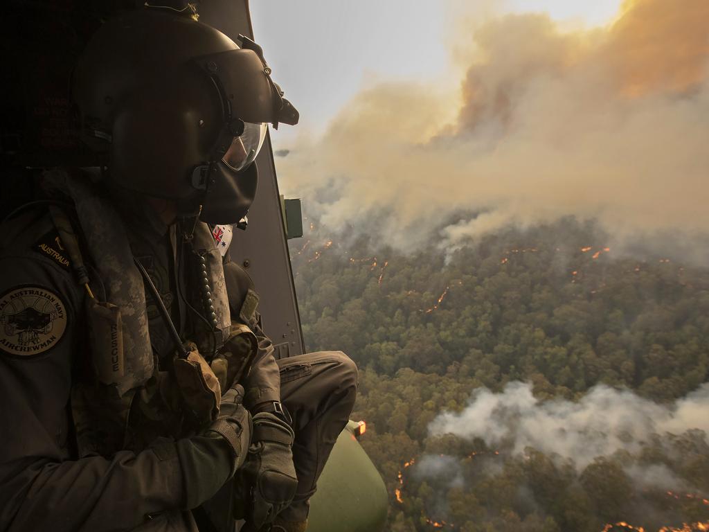 Royal Australian Navy Aircrewman Leading Seaman Ben Nixon of 808 Squadron, assesses the Tianjara Fire in the Moreton and Jerrawangala National Parks out of an MRH90 Taipan Military Support Helicopter. Picture: ADF