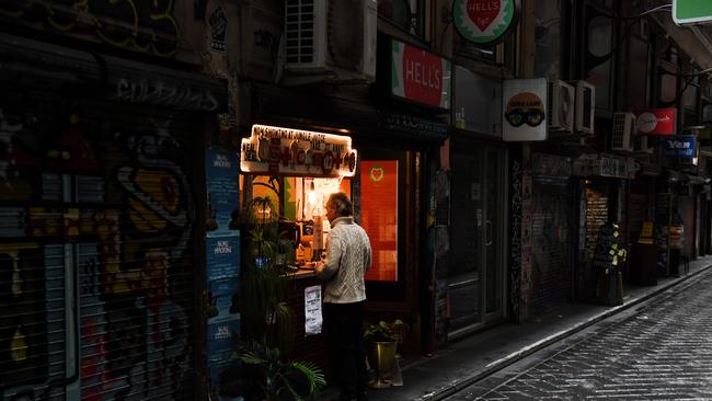 A man orders from a cafe in a small deserted laneway usually packed with open cafes and people during their lunchtime.