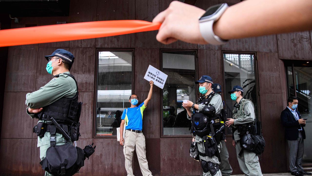 Riot police stand guard near a pro-democracy protester on Friday. Picture: Anthony Wallace/AFP