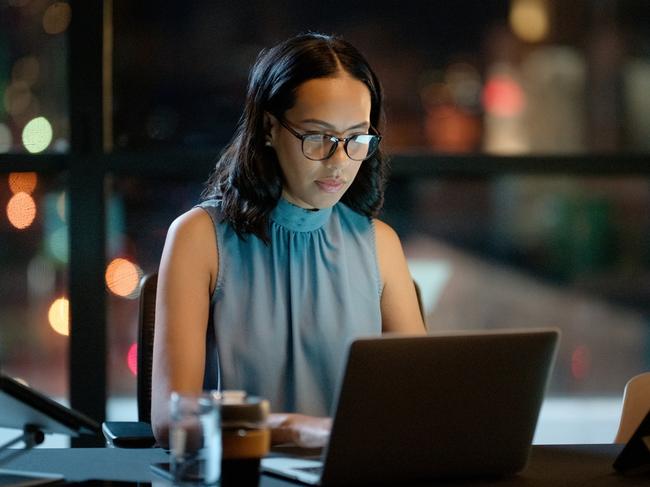 Laptop, serious and business woman typing, reading email or working on project in startup office at night. Computer, professional and designer with deadline to research online or planning with bokeh