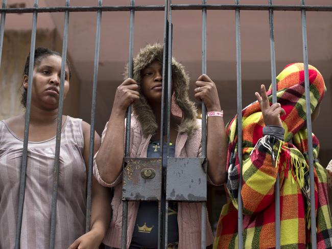 People stand behind a gate at the entrance of an abandoned residential apartment building in the middle class Flamengo neighborhood of Rio de Janeiro, Brazil, Tuesday, April 7, 2015. Squatters invaded the residence that Brazil's one-time richest man was supposed to transform into a luxury hotel, ahead of the 2016 Olympic games and are demanding city officials put them into social housing. (AP Photo/Silvia Izquierdo)