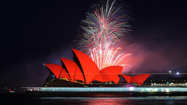 A stunning fireworks show behind the Opera House that is glowing red. Picture: AAP Image/Steven Saphore