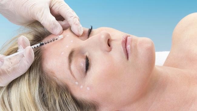 Woman lying down receiving botox injection in her forehead.