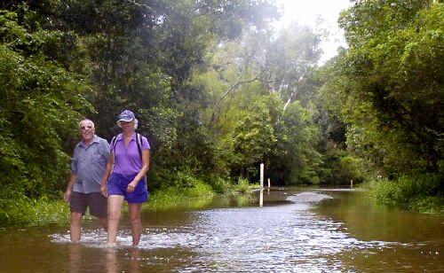 Grays Lane resident Isabel Reed and friend John Payne walk through floodwater to reach Mr Payne’s car after the Tyagarah road was cut. . Picture: Cathy Adams