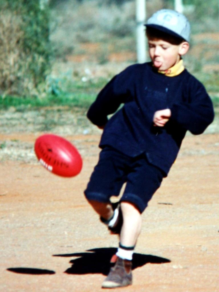 A young Jack aged six kicks a football while holidaying at Broken Hill.