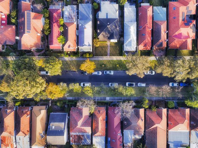 Leafy suburb on Sydney Lower North shore with sky-rocketed real estate property prices - top down aerial view over quiet street between houses with green trees and parked cars. Australian housing generic