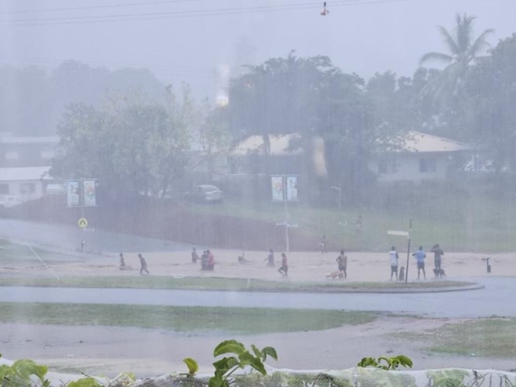 In Wujal Wujal, people can be seen playing in floodwaters despite sightings of crocodiles.