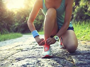 young woman runner tying shoelaces on stone trail